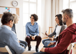 smiling counselor in group therapy discussing intensive outpatient program benefits