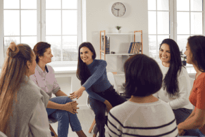a group of women sit in a circle and talk about the purpose of women's rehab