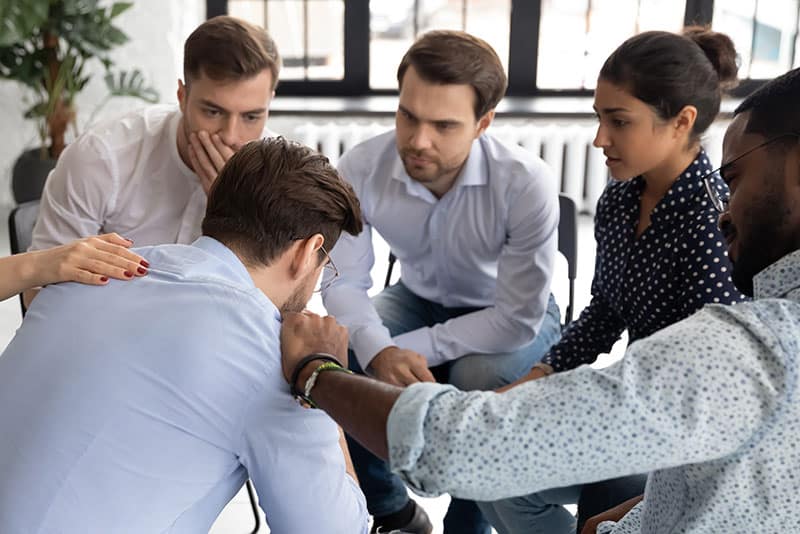 people in group therapy comforting a participant after enrolling in a detox treatment program