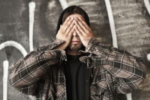 man with addiction covering eyes wondering about meth addiction causes