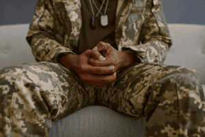 close-up of person with hands folded wearing fatigues looking for answers to the question what is ptsd