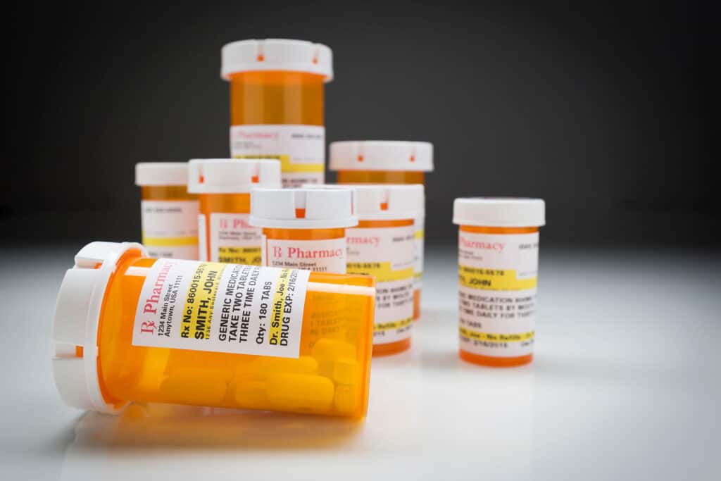 several pill bottles on a countertop against a black background as examples of opiates and opioids