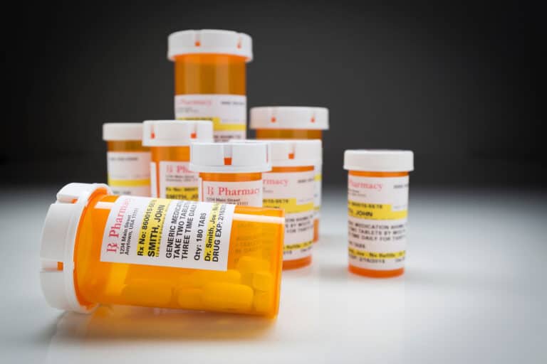 several pill bottles on a countertop against a black background as examples of opiates and opioids